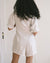 white linen romper with pockets, puff sleeves, and button front