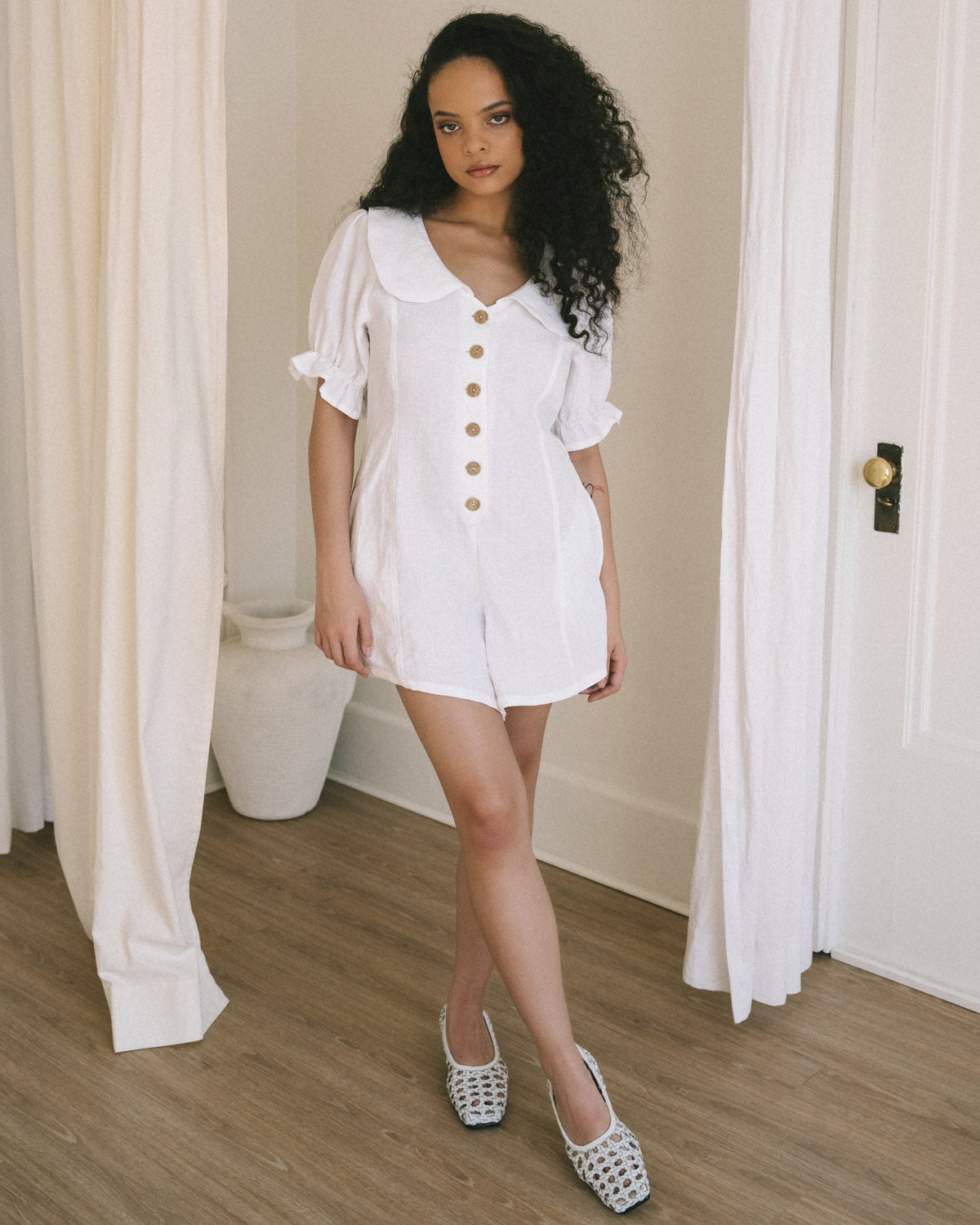 white linen romper with pockets, puff sleeves, and button front